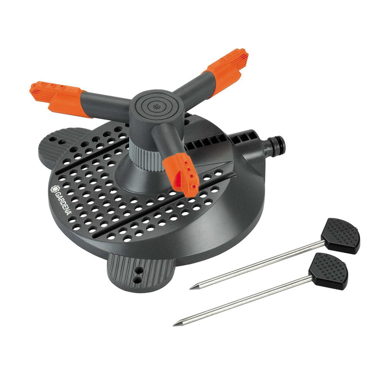 Aspersor circular GARDENA Samba Classic con base negra, brazos giratorios naranjas y piquetas de fijación metálicas.