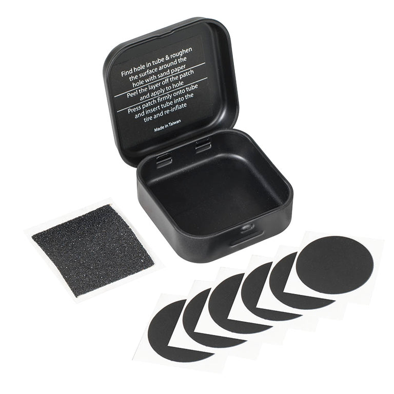 Kit de reparación de pinchazos RATIO abierto con 6 parches autoadhesivos, lija y estuche metálico negro.