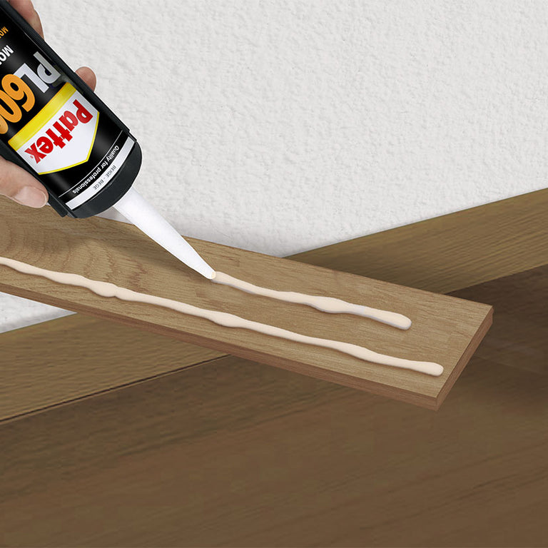 Aplicación de adhesivo Pattex PRO600 en cordones sobre una pieza de madera para montaje en pared.