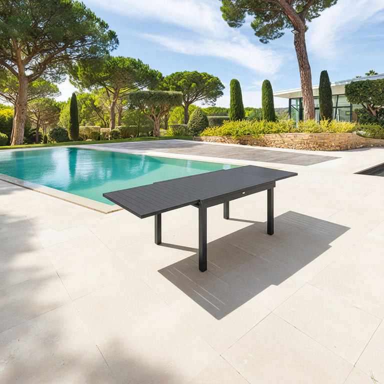 Mesa de jardín extensible Piazza color grafito en terraza con piscina.