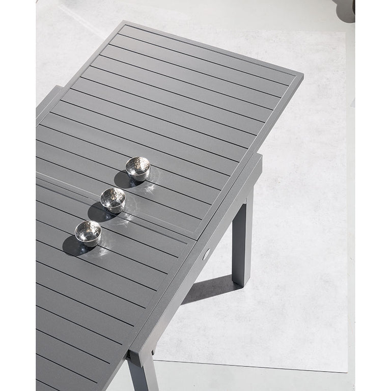 Primer plano del tablero de aluminio de la mesa Piazza grafito mostrando el sistema de extensión deslizante.