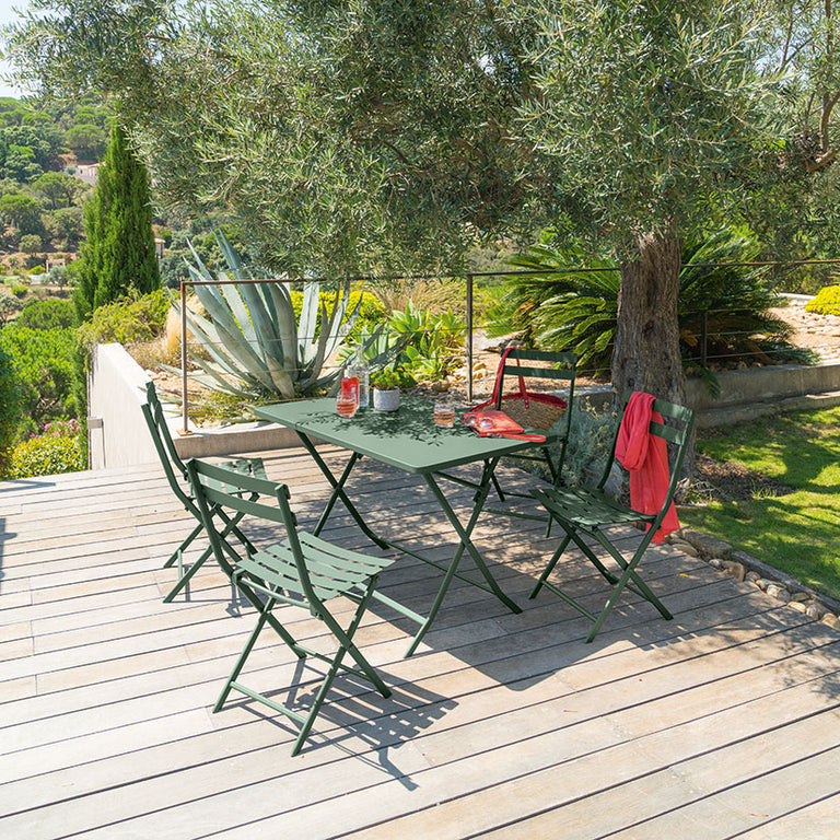 Comedor exterior en terraza de madera con mesa y sillas verdes plegables