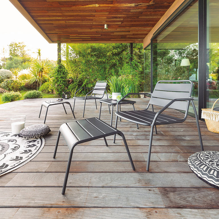 Conjunto de muebles de jardín Phuket Graphite de 5 piezas dispuesto en una terraza de madera con vistas al jardín.