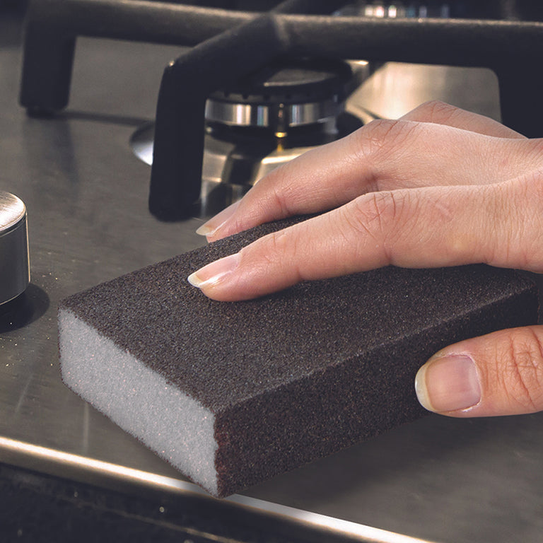 Limpieza de placa de cocina de acero inoxidable con estropajo mágico negro antirayaduras