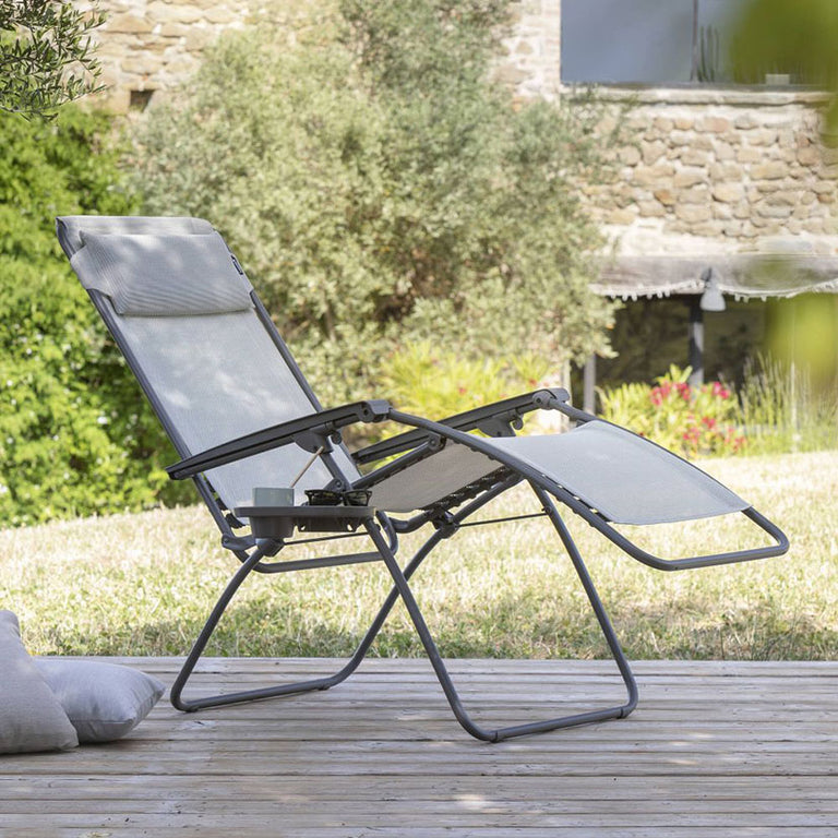 Sillón Lafuma RClip en terraza con bandeja posavasos lateral y acabado resistente.