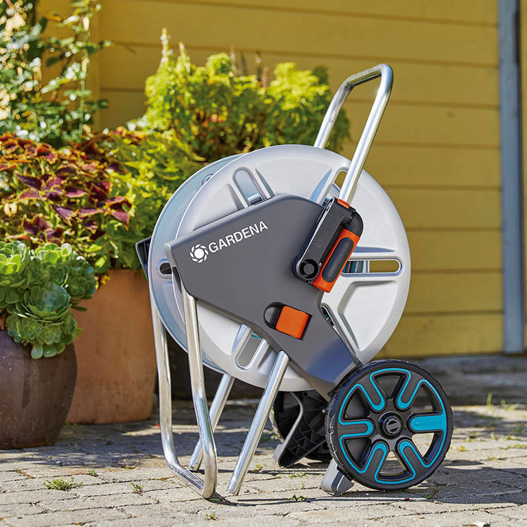 Carro GARDENA CleverRoll M Metal en jardín, diseño compacto y ruedas de transporte resistentes.
