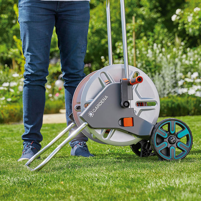 Uso ergonómico del carro GARDENA CleverRoll M Metal para transporte cómodo sobre césped.