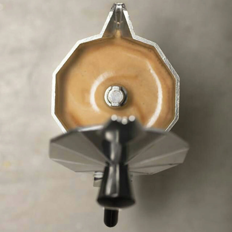 Primer plano superior de cafetera moka Oroley con café espresso recién preparado y espuma