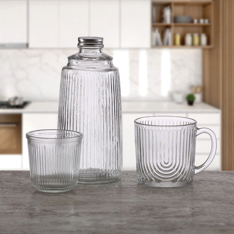 Botella y vaso de cristal Versa en ambiente de cocina moderna junto a una taza de café