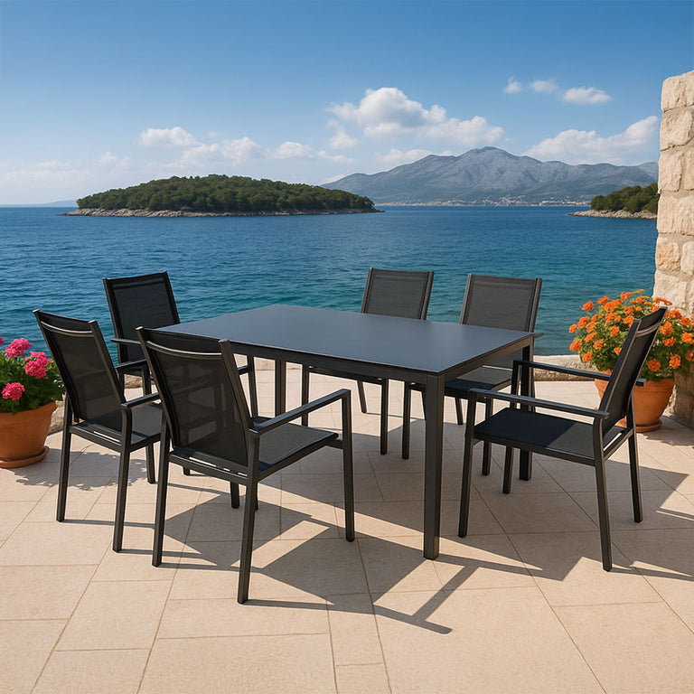 Muebles de exterior Terrazza instalados en una terraza de madera frente al mar con flores decorativas.