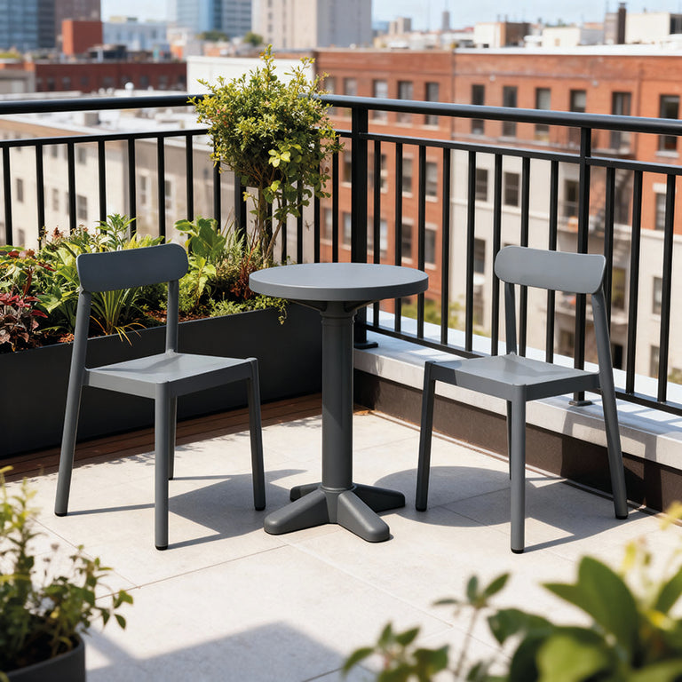 Set de balcón IVY de RESOL compuesto por mesa y sillas apilables en una terraza urbana con plantas.