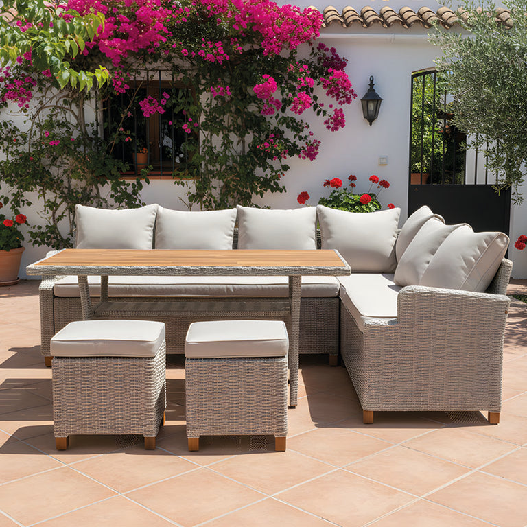 Mobiliario de terraza Canaima compuesto por sofá rinconera gris y mesa de comedor en patio exterior decorado.