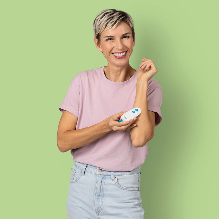Usuario sonriente sosteniendo el dispositivo compacto Ecomed para alivio de picaduras