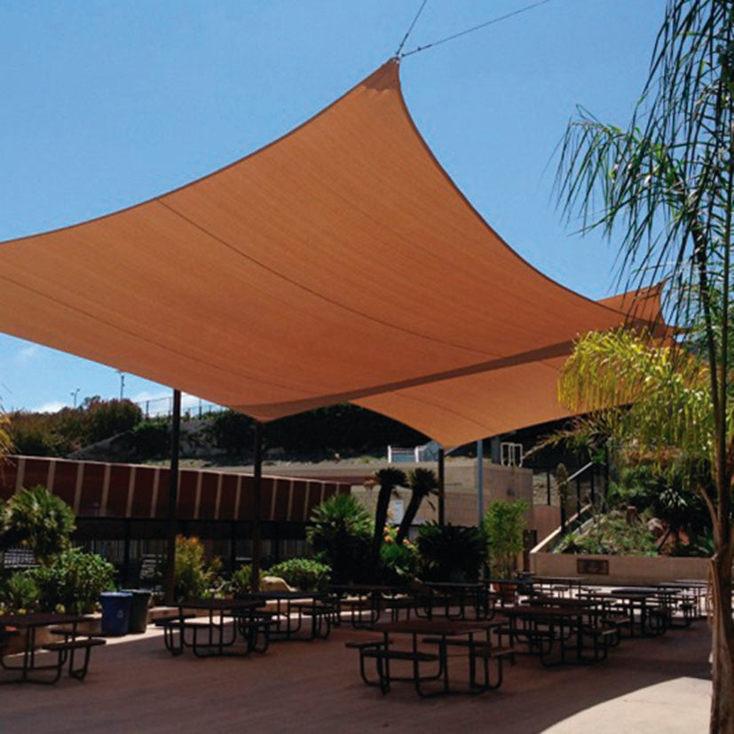 Toldo vela color arena instalado en terraza exterior con herrajes de tensión profesionales.