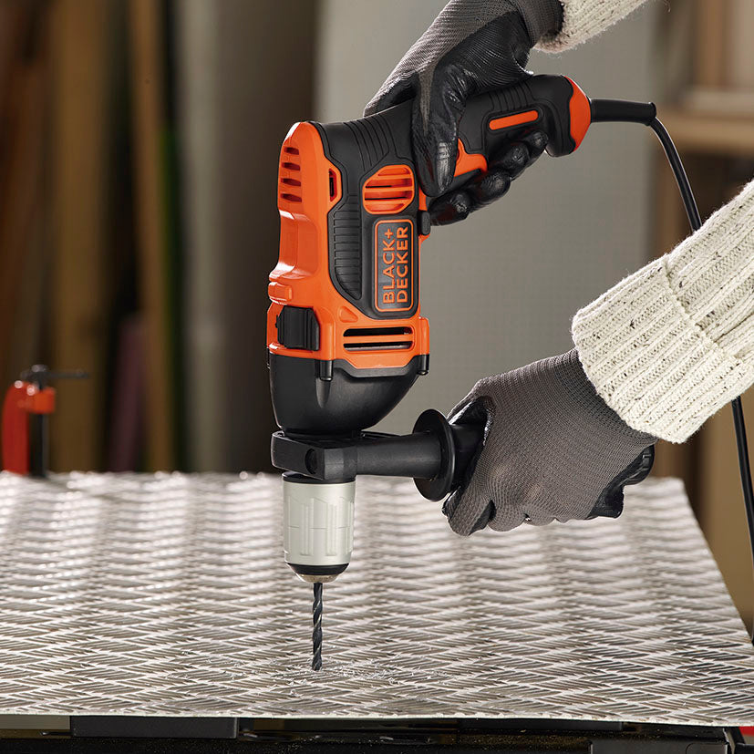 Taladro Black+Decker BEH850K-QS perforando una plancha de metal estriado demostrando su potencia de 850W.
