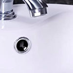 Detalle de embellecedor cromado instalado en el orificio de rebosadero de un lavabo cerámico.