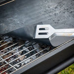 Uso de espátula sobre esterilla protectora de barbacoa para evitar suciedad en la rejilla