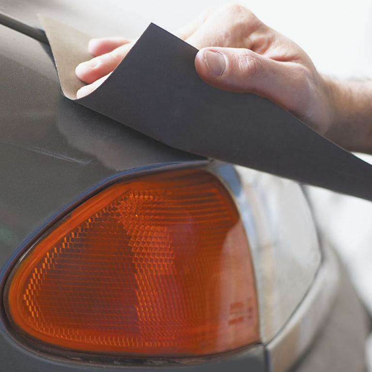 Lijado manual en húmedo sobre la carrocería de un vehículo con papel abrasivo impermeable.