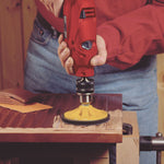 Uso de disco abrasivo con taladro eléctrico para decapar pintura sobre superficie de madera.