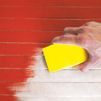 Lijado manual con taco amarillo sobre superficie de madera pintada de rojo