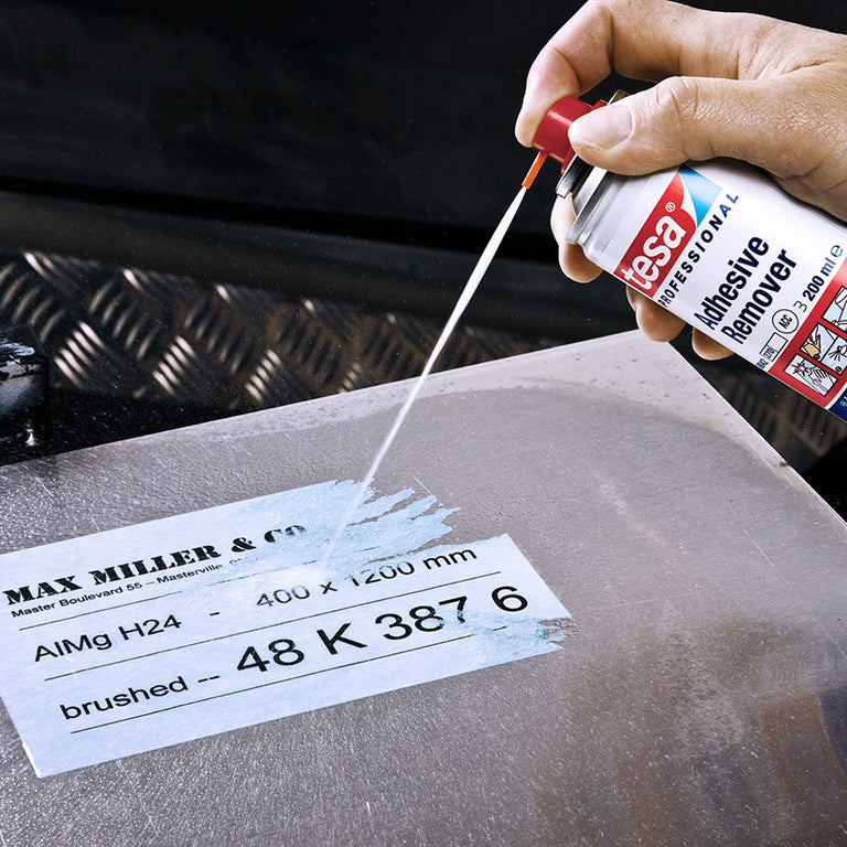 Uso de cánula de precisión del spray TESA 60042 para despegar una etiqueta adhesiva de una placa de metal.