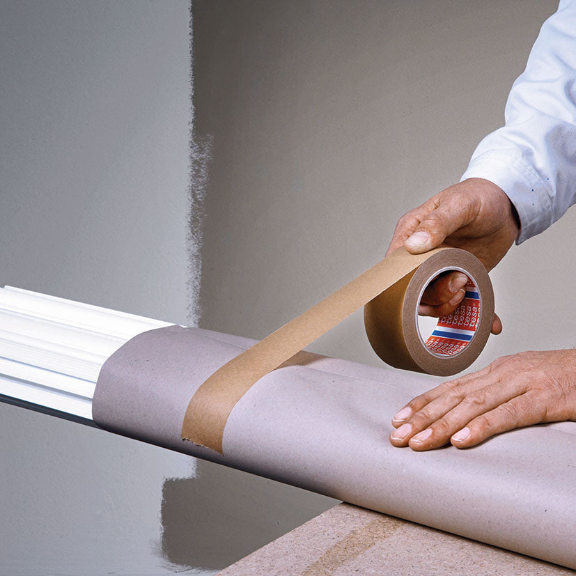 Uso de cinta adhesiva TESA para fijar papel protector en trabajos de pintura y bricolaje.
