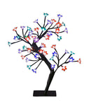 Árbol decorativo Prunus de 45 cm con luces LED de colores y base de soporte negra sobre fondo blanco.
