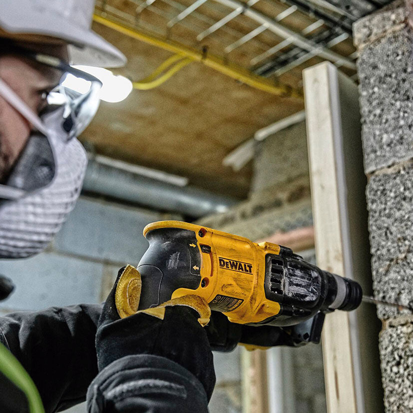 Detalle de uso del martillo combinado DEWALT D25133K-QS perforando un bloque de construcción en interiores