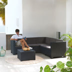 Ambiente de terraza con hombre relajado en sofá esquinero Oasis de resina imitación ratán.