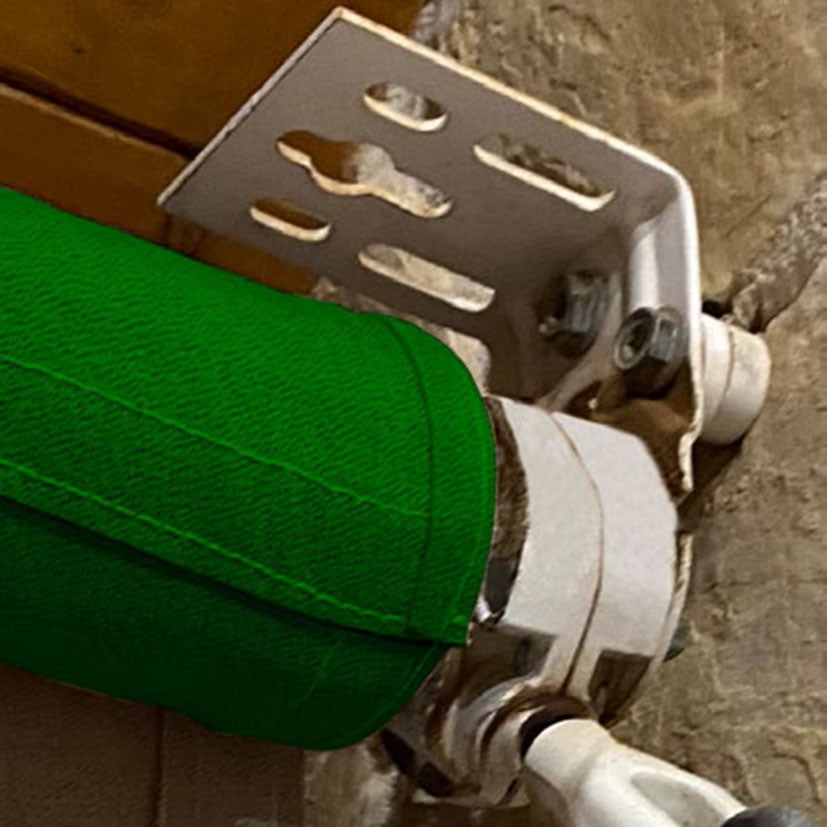 Detalle de instalación de soporte MICEL TLD08 sujetando el mecanismo de un toldo verde en pared.