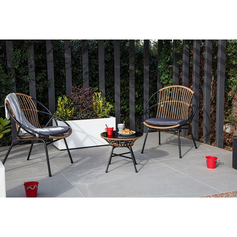 Conjunto de jardín Bistro con dos sillones de ratán sintético y mesa redonda de cristal en terraza moderna.