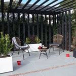 Sillones de exterior con estructura metálica negra y cojines grises situados bajo una pérgola de diseño.