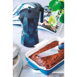Uso de cafetera MONIX Induction Noir en cocina junto a un bizcocho recién horneado.
