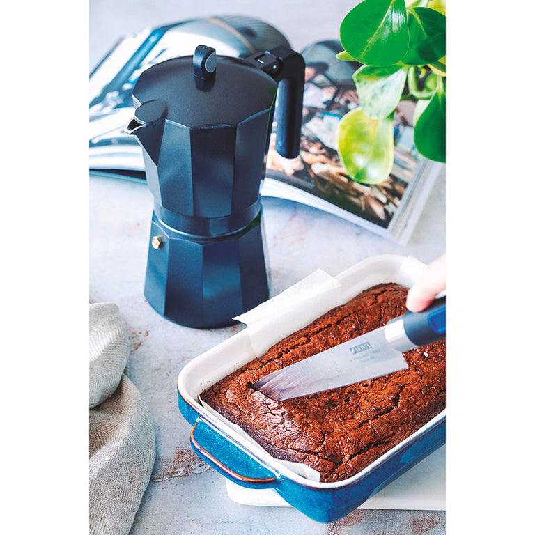 Uso de cafetera MONIX Induction Noir en cocina junto a un bizcocho recién horneado.