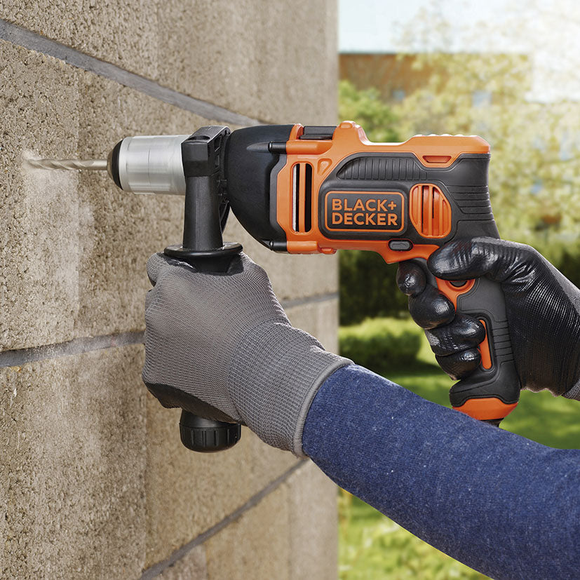 Uso del taladro percutor Black+Decker perforando una pared de bloques de hormigón con precisión.