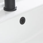 Detalle de embellecedor negro instalado en el orificio de rebosadero de un lavabo cerámico blanco