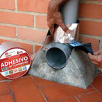 Aplicación manual de cinta bituminosa sobre tubería de PVC y base de hormigón para sellado estanco.