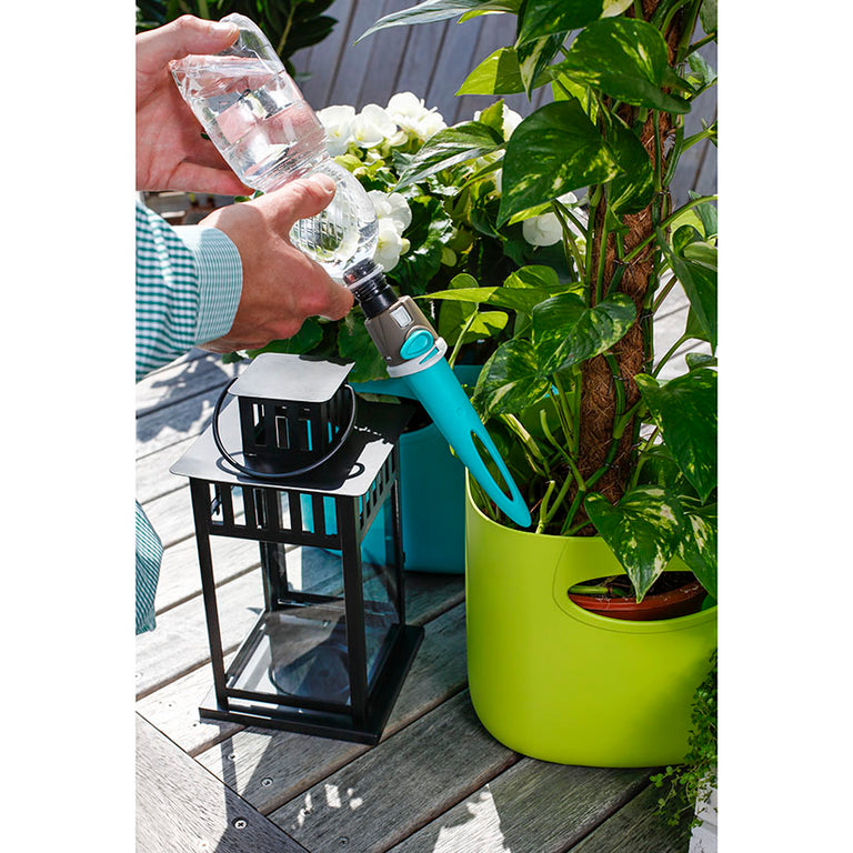 Instalación de estaca de riego Aquaflora con botella de agua en maceta de exterior