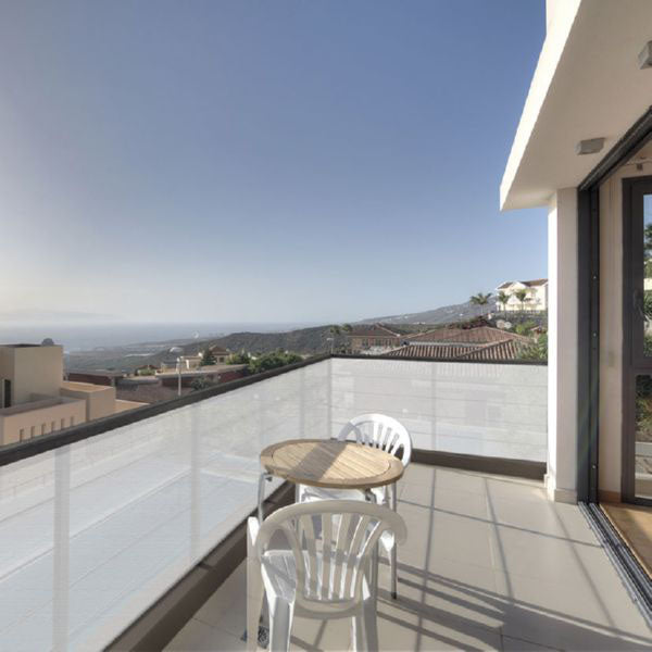 Malla de ocultación blanca instalada en barandilla de terraza con vistas al mar