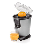 Uso del exprimidor Princess 160W exprimiendo media naranja directamente sobre un vaso de zumo fresco.