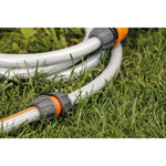 Conector reparador LISTA uniendo dos tramos de manguera de riego sobre césped de jardín