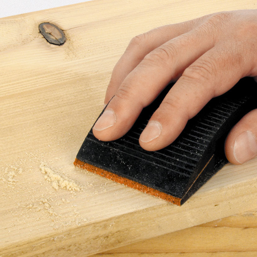 Persona lijando una tabla de madera con un taco de lijado manual y papel Wolfcraft