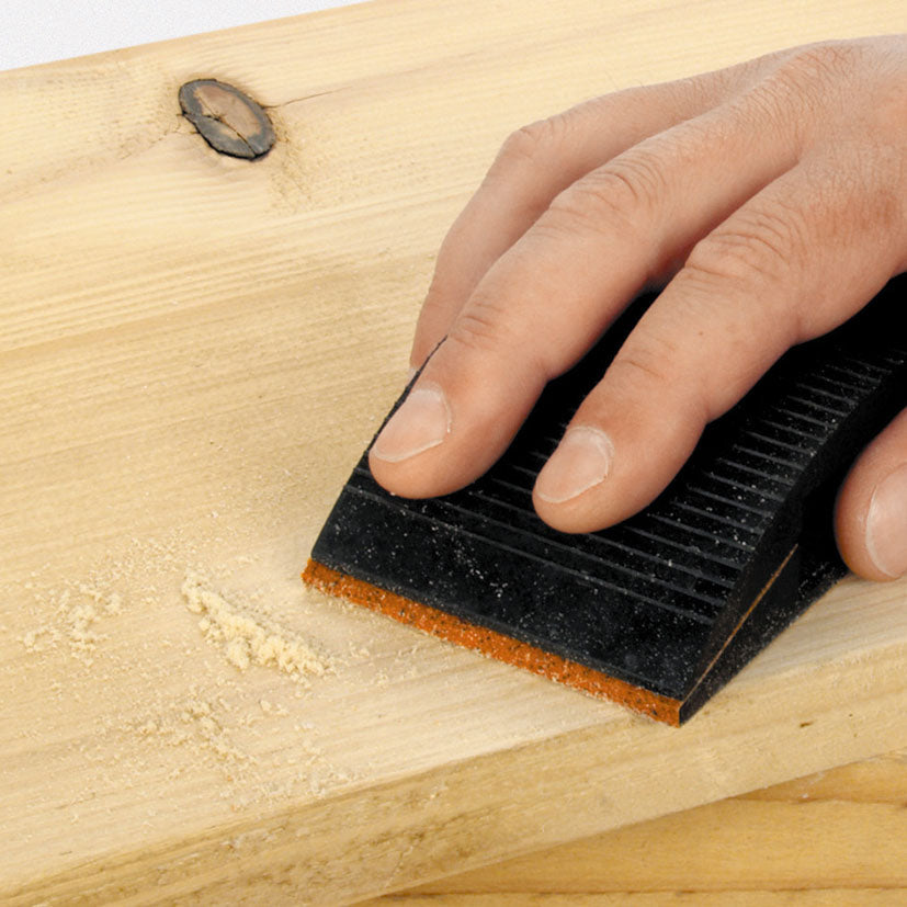 Primer plano de lijado manual sobre madera mostrando la flexibilidad de la hoja de lija