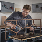 Uso de cepillo Wolfcraft para limpiar una estructura de hierro oxidada en un banco de trabajo de taller.