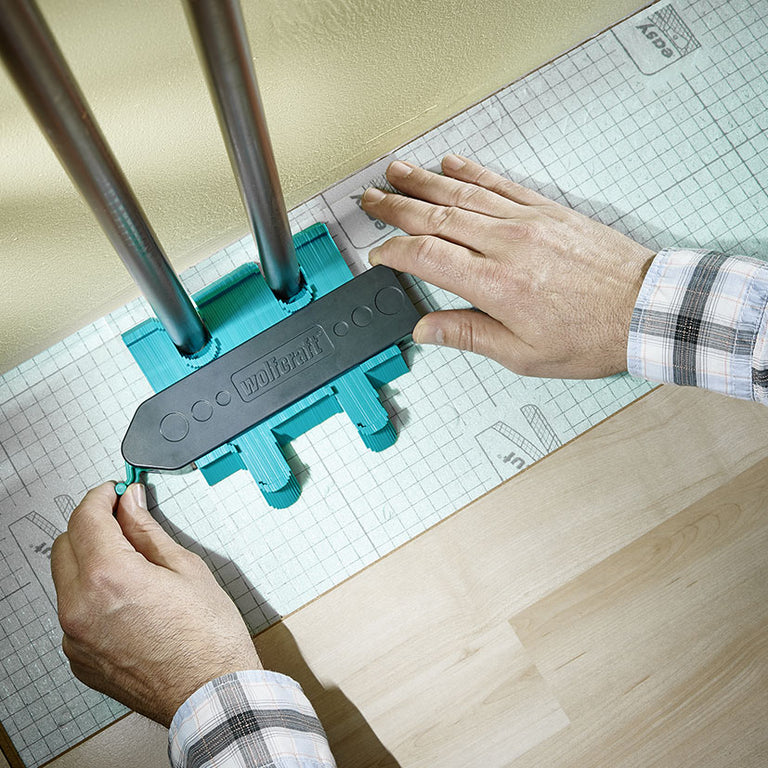 Uso del copiador de contornos Wolfcraft para medir el perfil de tuberías de calefacción en suelo laminado