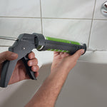 Aplicación de silicona blanca en junta de bañera con pistola Wolfcraft MG 100 de alta precisión.