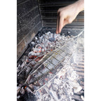 Pescado cocinándose directamente sobre las brasas con la parrilla de acero inoxidable Sauvic.