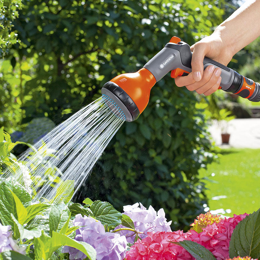 Uso de la pistola GARDENA Classic con chorro de ducha suave para regar flores en el jardín.