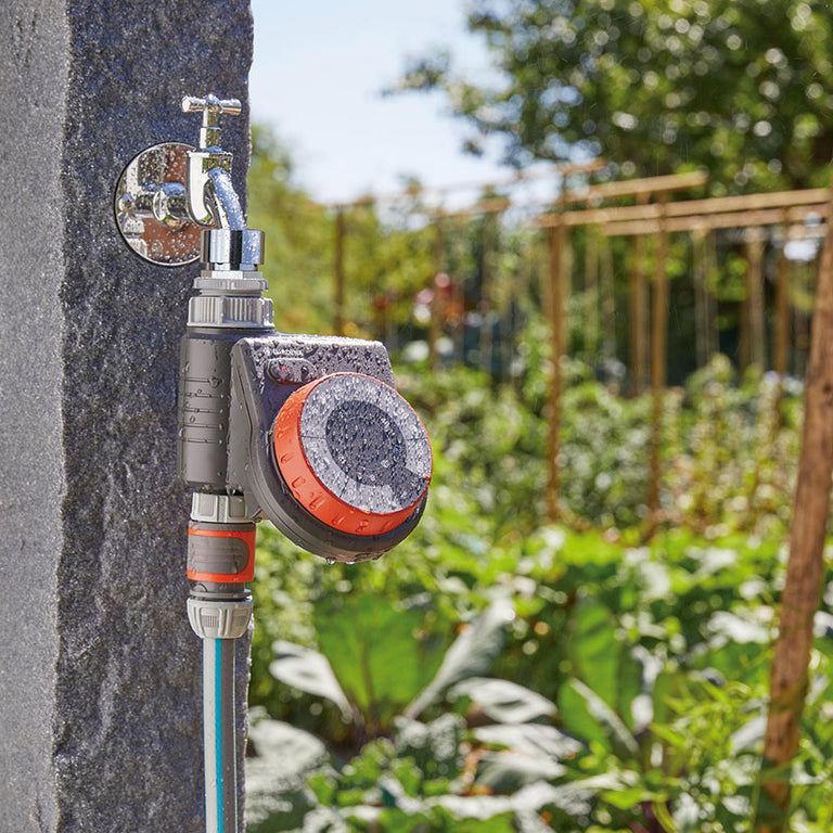 Programador GARDENA Easy montado en grifo de jardín funcionando en un huerto exterior