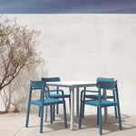 Conjunto de mesa blanca Noa y sillas azules Elba de Resol en terraza exterior de diseño moderno.
